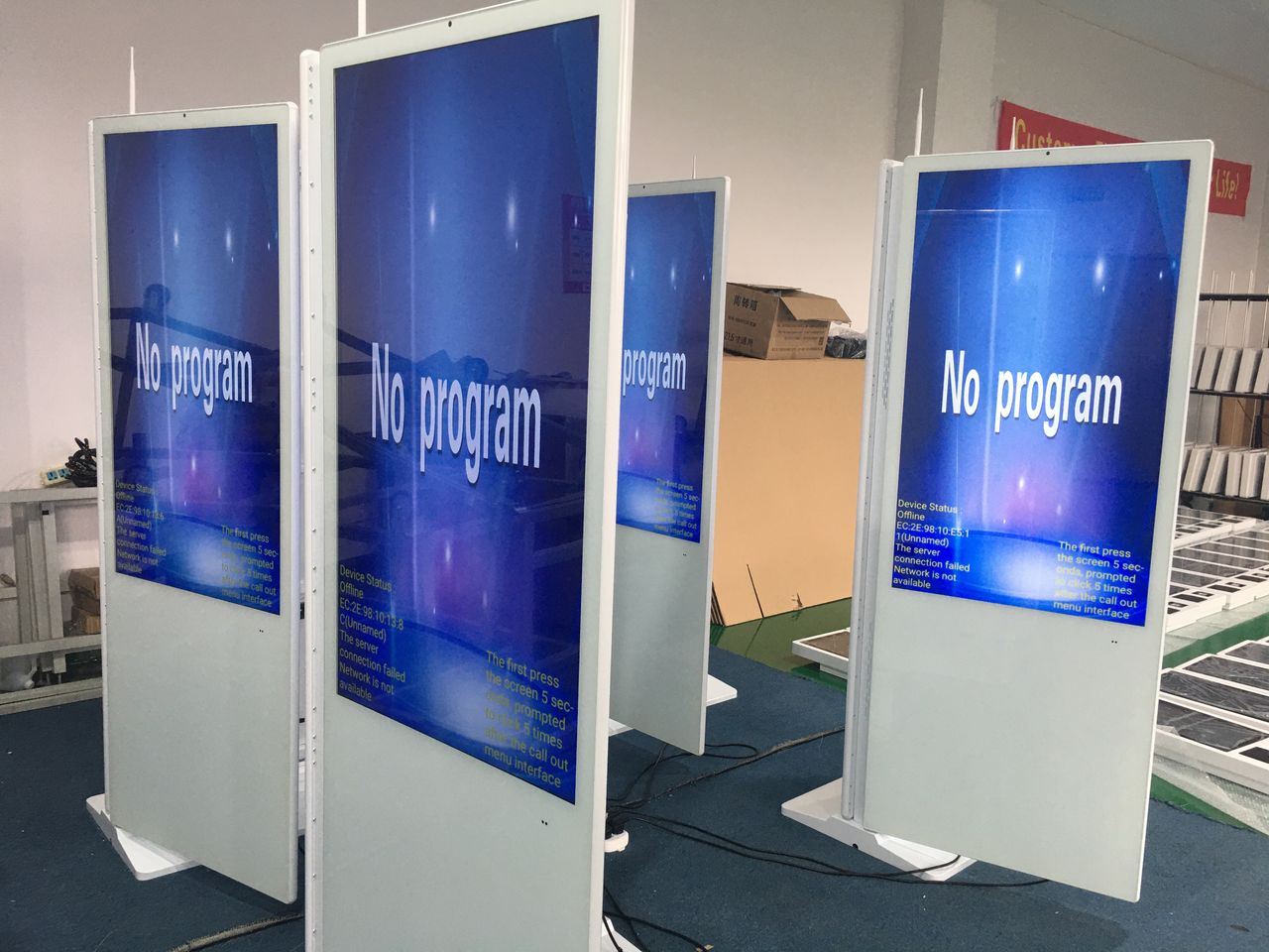 Digital display screens with 'No program' message on a blue screen, indoors.