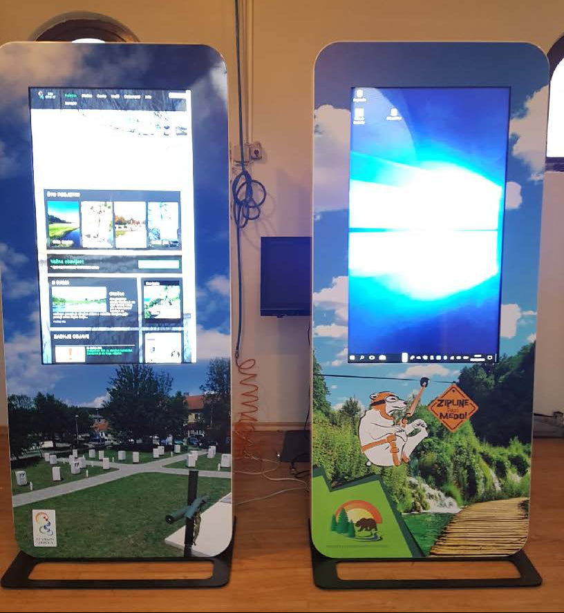 Two digital display stands with screens showing outdoor scenes and graphics.