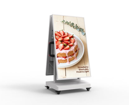 A freestanding A-frame digital menu board on a white wheeled base, displaying a photo of a strawberry shortcake with text reading 'Strawberry Shortcake, Fresh & Light' on a clean white background.