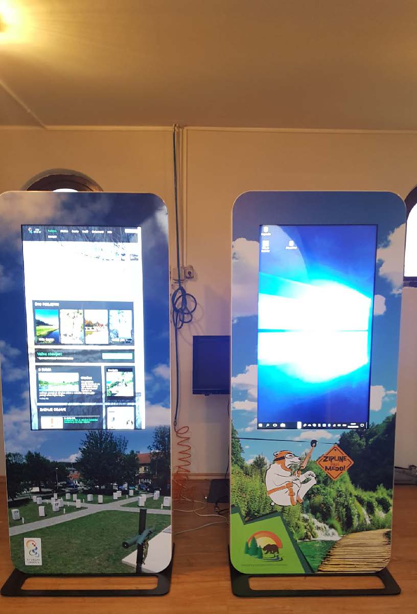 Two digital display stands with screens showing outdoor scenes and graphics.